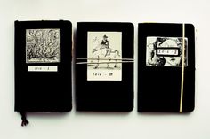 three black notebooks with pictures on them