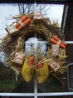 a wreath made out of hay, carrots and burlocks is hanging on the window sill