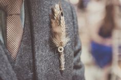 a man wearing a suit and tie with a feather pinned to his lapel pin