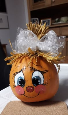 an orange painted pumpkin with a bow on it's head sitting on a table