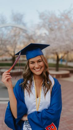 a woman wearing a blue graduation cap and gown posing for the camera with her arms crossed