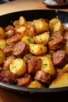 a pan filled with potatoes and meat on top of a wooden table