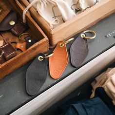 three leather keychains sitting on top of a wooden box next to other items