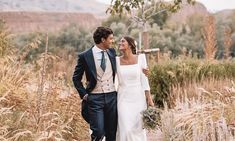 a bride and groom walking through tall grass