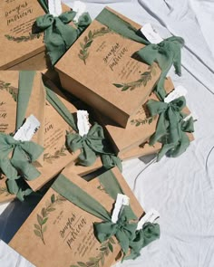 several brown boxes with green ribbons tied around them on a white cloth covered tablecloth