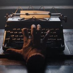 a person's hand on an old fashioned typewriter