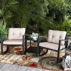 two chairs sitting on top of a rug next to a table and potted plant