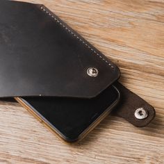 two leather wallets sitting on top of a wooden table