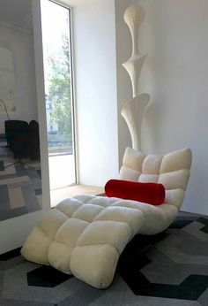 a white chair sitting in front of a window next to a black and red rug