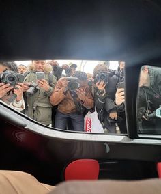 a group of people taking pictures in a car mirror