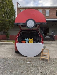 the back end of a red car with stuffed animals in it's trunk and ladder