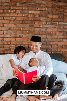 a man reading a book to two children while sitting on a bed with brick wall in the background