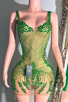 a mannequin with green and gold sequins in front of a mirror