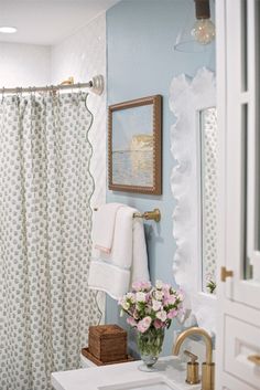 a white sink sitting under a bathroom mirror next to a shower curtain covered in flowers