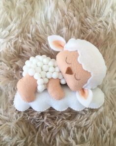 a stuffed sheep laying on top of a fluffy carpet covered in white balls and beads