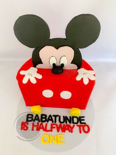 a cake shaped like mickey mouse with the words babatunde is halfway to one