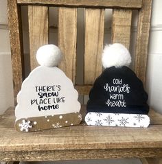 two beanies sitting on top of a wooden bench with snowflakes around them