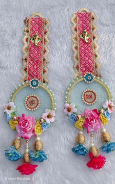 pair of pink and blue earrings with flowers on white furnishing, top view