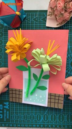 someone is making some flowers out of paper and glue on the side of a card