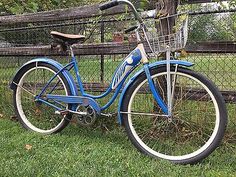 a blue bicycle parked in front of a fence with a basket on the back tire