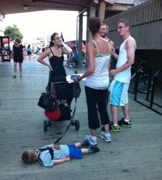 a group of people standing next to each other on a sidewalk with a baby in a stroller