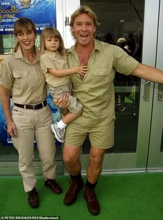 a man and two children posing for a photo in front of a glass door with an advertisement behind them