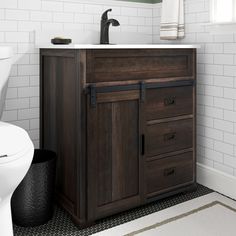 a white toilet sitting next to a wooden cabinet in a bathroom under a mirror and sink