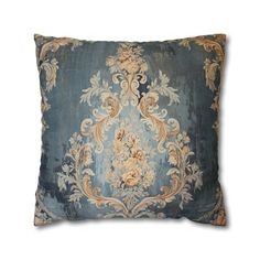 a blue and gold pillow with an ornate design on the front, sitting on a white background