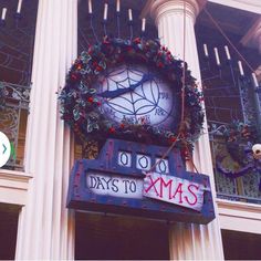 a large clock mounted to the side of a building with christmas decorations on it's sides