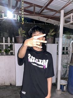 a young man holding his fingers up to the camera while wearing a t - shirt