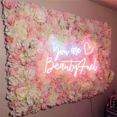 a pink and white flower wall with the words you're beautiful on it in neon lights