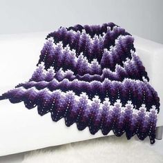 a crocheted purple blanket on top of a white couch