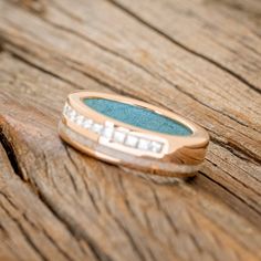 a gold ring with blue and white stones sitting on top of a piece of wood