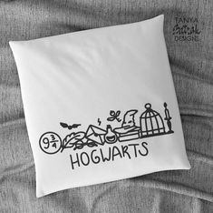 the hogwarts pillow is laying on top of a bed with grey sheets and pillows