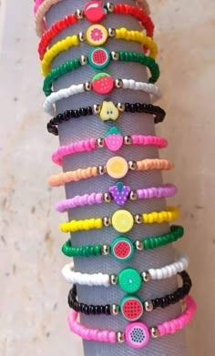 a person's hand holding a stack of bracelets with fruit charms on them