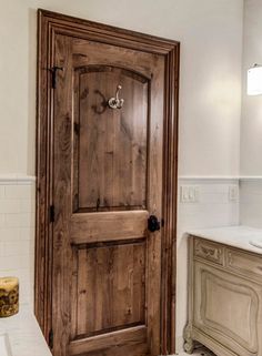 a wooden door in a bathroom next to a sink