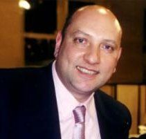 a man in a suit and tie smiling at the camera