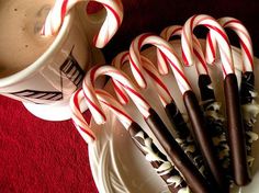 some candy canes are on a plate next to a cup