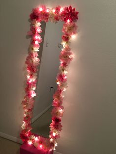 a mirror that has flowers on it and lights in the shape of a flower frame