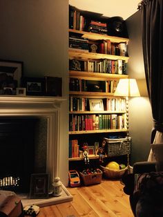 a living room filled with furniture and a fire place in front of a book shelf