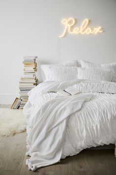 a white bed sitting next to a stack of books on top of a wooden floor