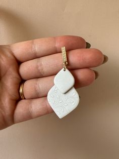 a hand holding a small white object in it's left hand, with a gold chain attached to it