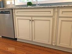 a kitchen with white cabinets and wood floors is pictured in this image, there is a dishwasher on the counter next to the sink