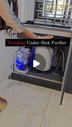 a woman is opening the under sink purifer