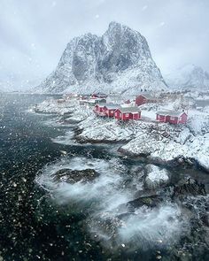 an aerial view of some houses and mountains in the snow, with water running through it