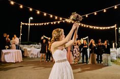 a woman in a wedding dress holding up a bouquet