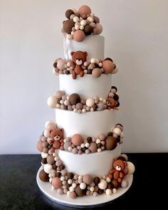 a three tiered white cake with teddy bears on the top and balls all around it