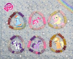 four bracelets with pony designs on them sitting next to a rainbow - colored background