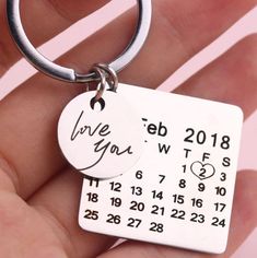 a hand holding a keychain with a date on it that says love you