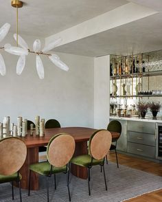 a dining room table with green chairs around it